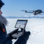 DJI RC Pro 2 - een afstandsbediening met openklapbaar scherm - man op een sneeuvlakte die deze afstandsbediening gebruikt om de DJI MAvic 4 Pro te vliegen