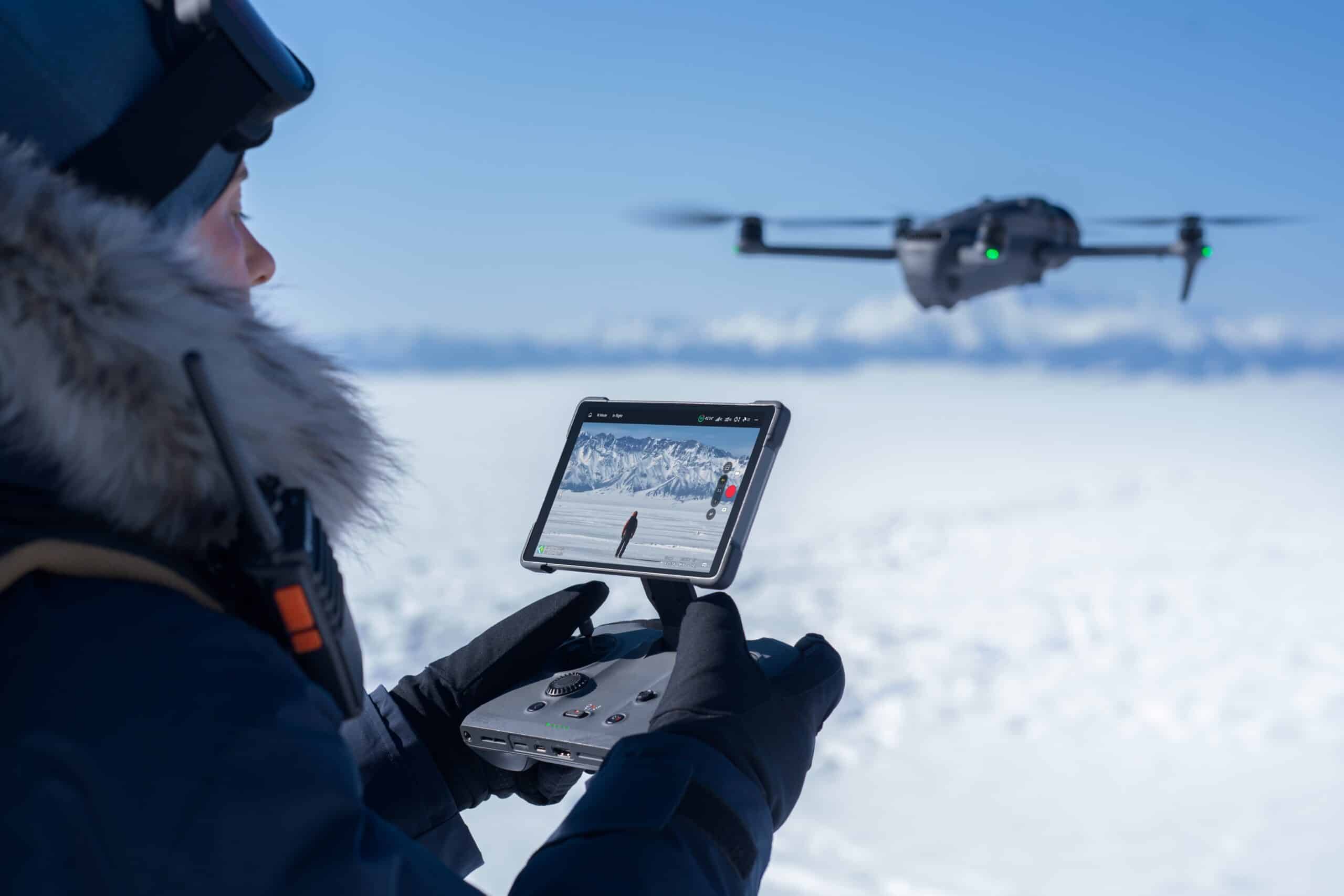 DJI RC Pro 2 - een afstandsbediening met openklapbaar scherm - man op een sneeuvlakte die deze afstandsbediening gebruikt om de DJI MAvic 4 Pro te vliegen